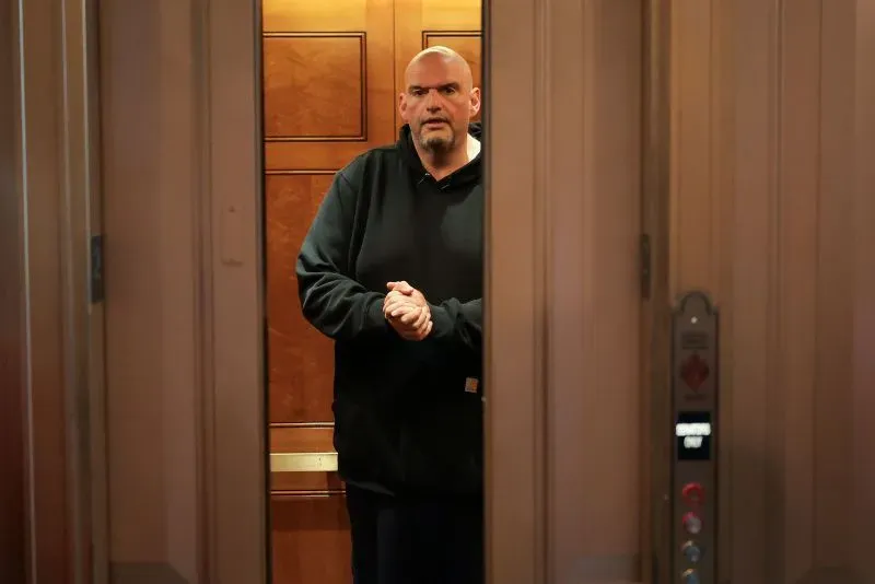 يظهر السيناتور جون فيترمان وهو يقف في مصعد، مرتديًا سترة سوداء، مع تعبير جاد، في سياق مناقشة الاحتجاجات والعنف في كاليفورنيا.