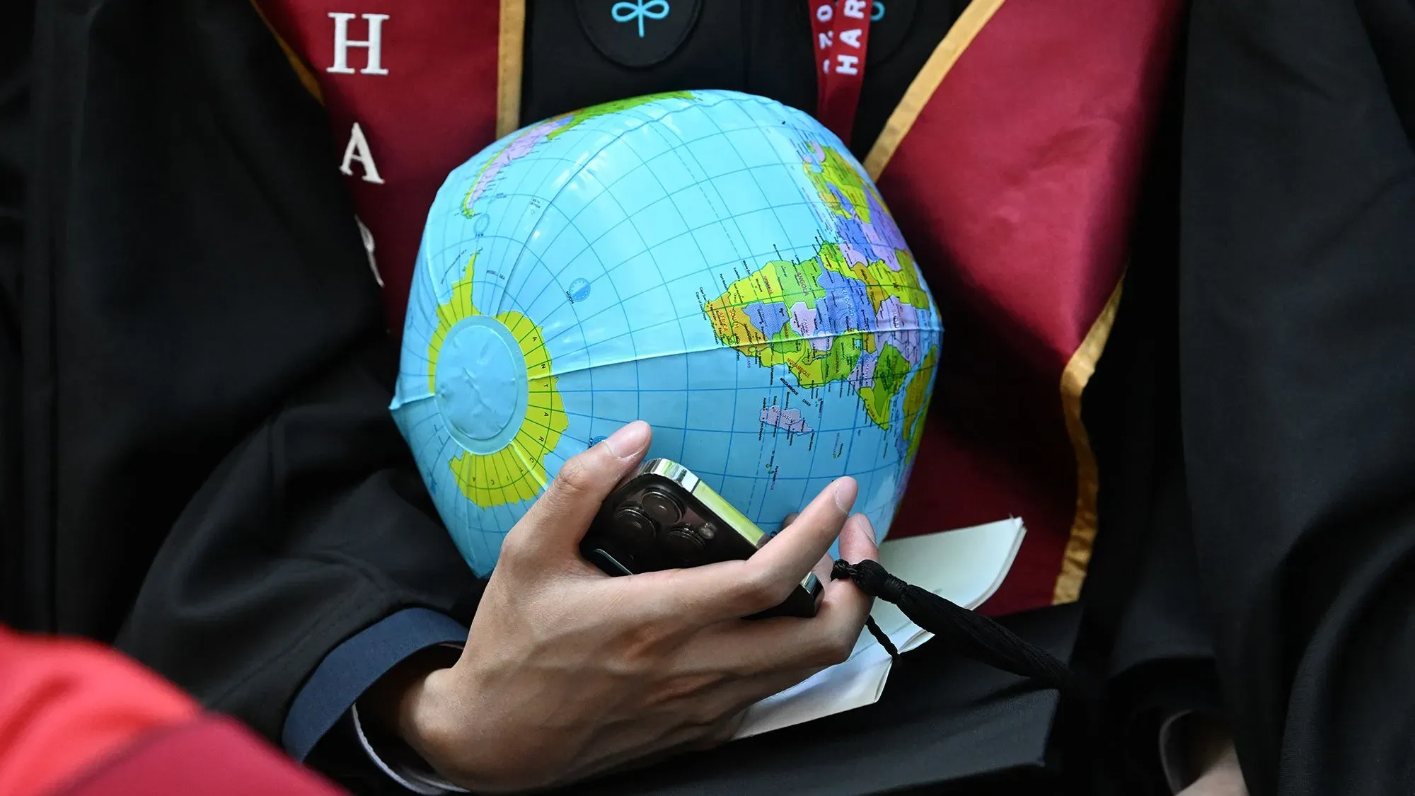 طالب يرتدي رداء التخرج ممسكًا بكرة أرضية صغيرة، مما يرمز إلى تأثير الطلاب الدوليين على الاقتصاد والتعليم العالي في الولايات المتحدة.