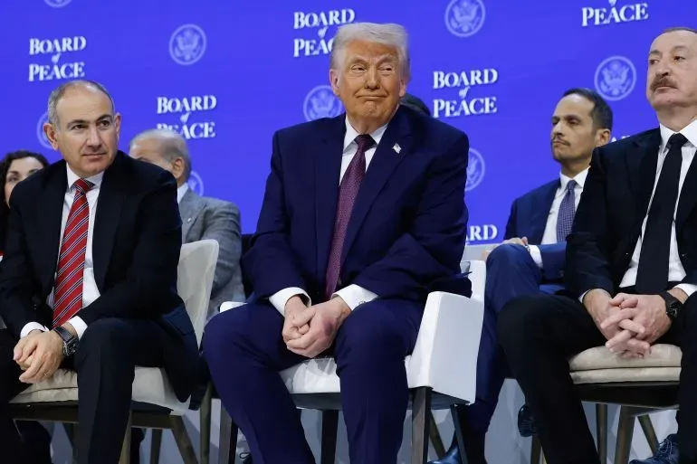 مجموعة من الرجال يجلسون على مقاعد في حدث يتعلق بالسلام، مع وجود شعار "مجلس السلام" في الخلفية، يبرز دورهم في محادثات حول مستقبل غزة.