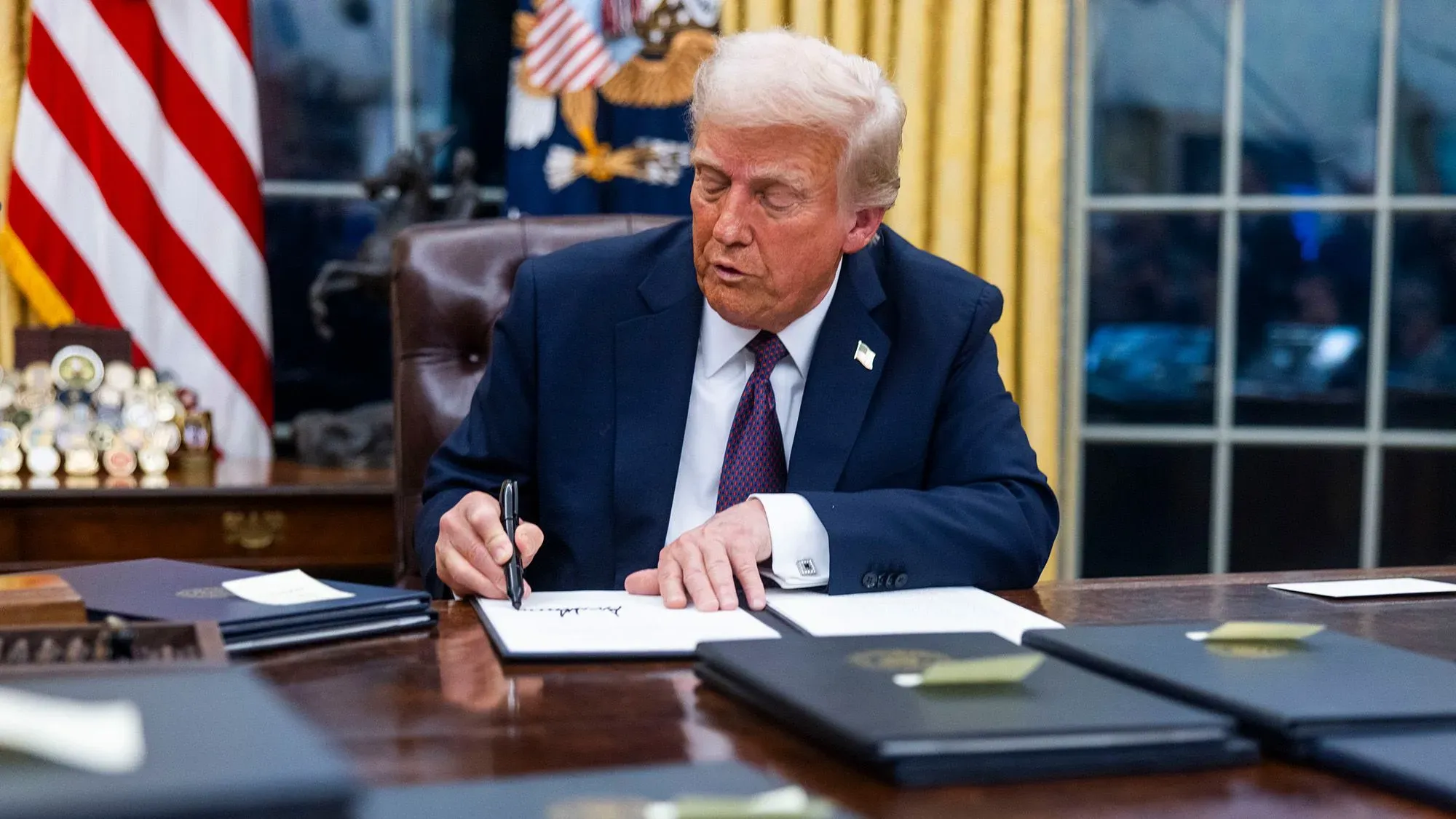 ترامب يوقع على أوامر تنفيذية في المكتب البيضاوي، مما يزيد من إجراءات ترحيل المهاجرين ويعزز سياسات الهجرة.