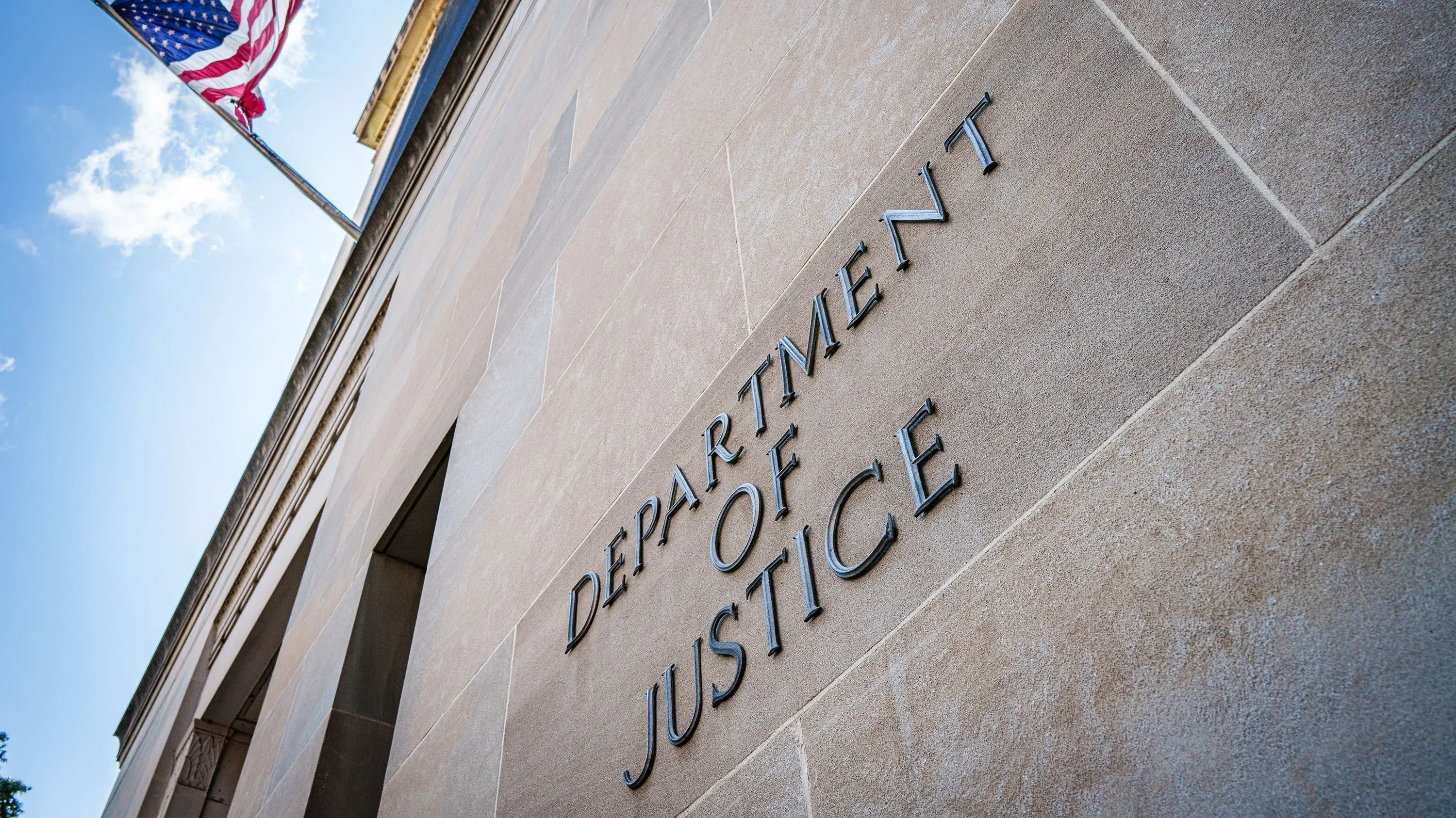 واجهة مكتب وزارة العدل الأمريكية، مع لافتة تحمل الاسم، وزي العلم الأمريكي في الخلفية. تعكس التغييرات في جهود إصلاحات الشرطة.