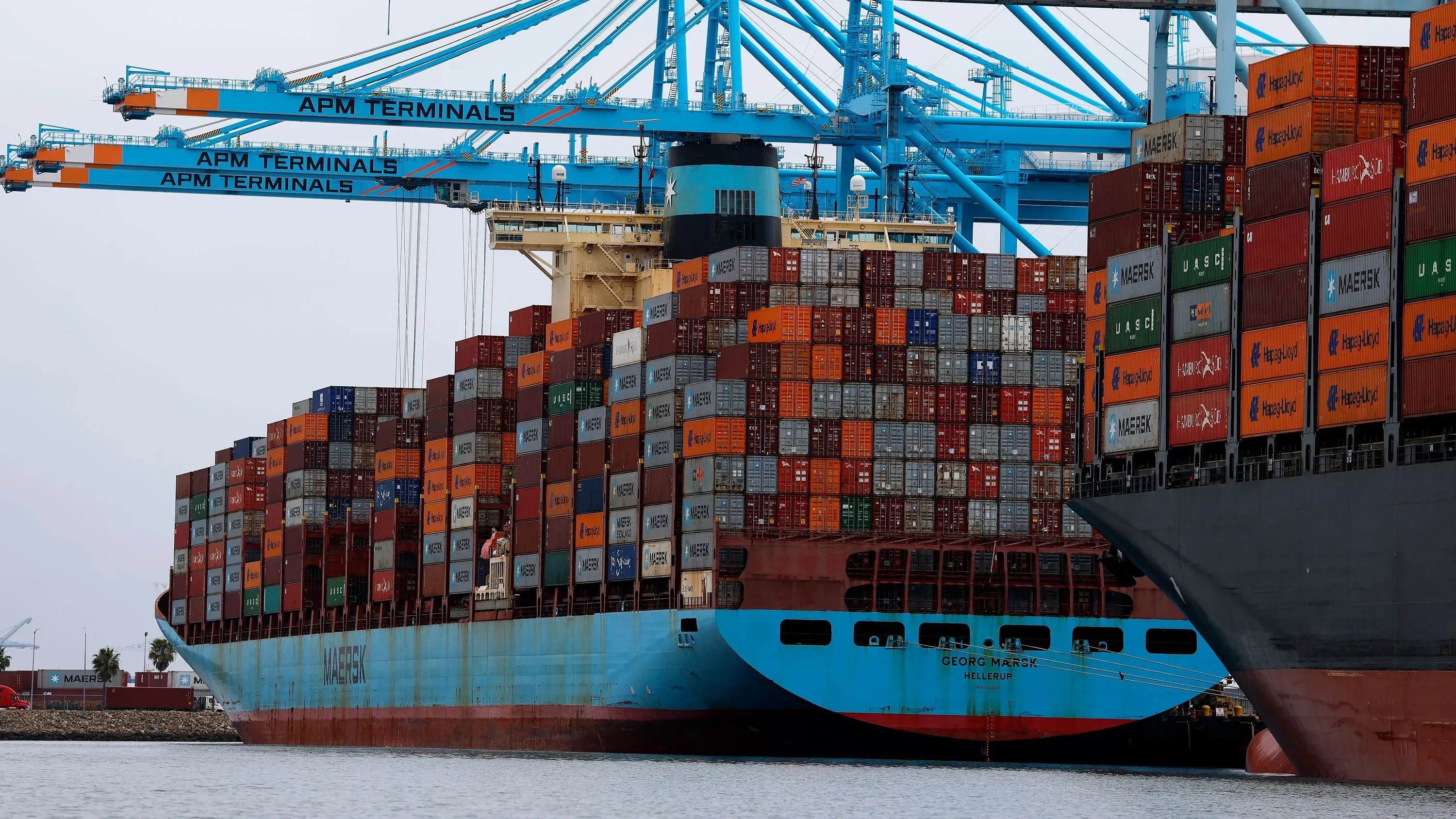 سفينة شحن محملة بالحاويات في ميناء، تمثل التوترات التجارية بين الولايات المتحدة والصين وتأثير التعريفات الجمركية على الاقتصاد.