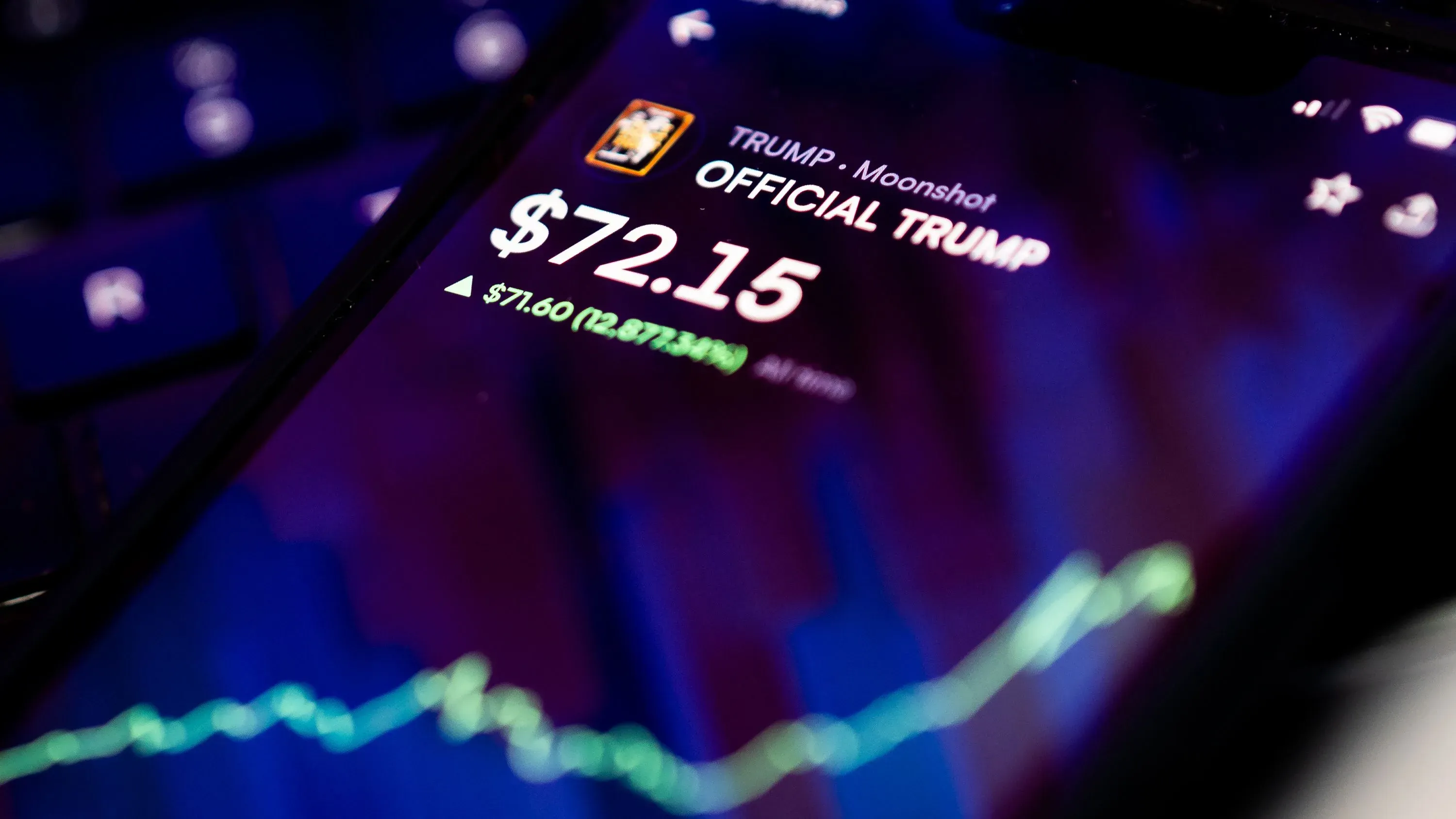 تظهر الصورة شاشة هاتف تعرض سعر عملة ترامب الرقمية، مع رسم بياني يظهر ارتفاع السعر إلى 72.15 دولار.