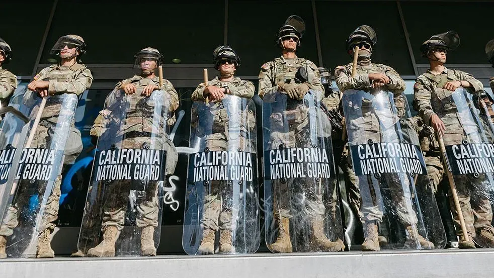 جنود من الحرس الوطني في كاليفورنيا يرتدون دروع الحماية ويقفون في صفوف، في إطار تعزيز الأمن خلال الاحتجاجات.