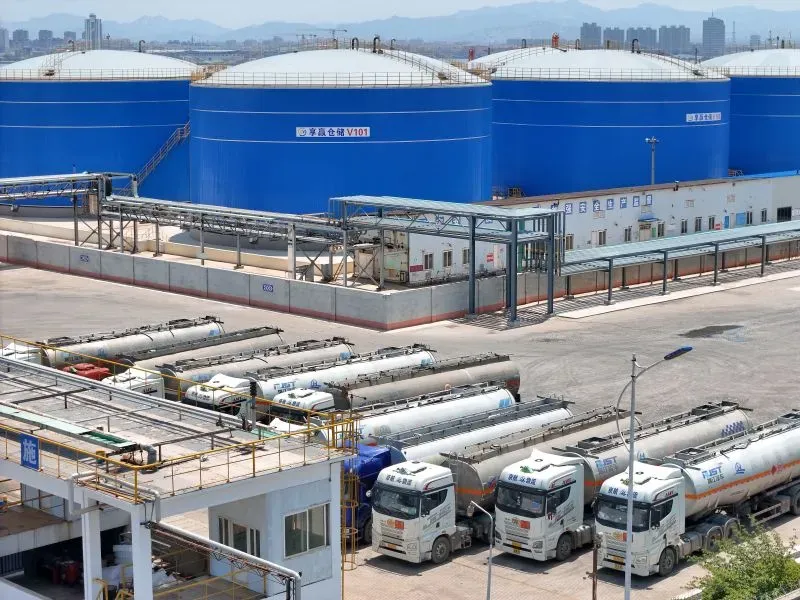 صهاريج تخزين النفط في منشأة صناعية، مع شاحنات نقل متوقفة في المقدمة، تعكس التركيز على إمدادات الطاقة العالمية وتأثير العقوبات المحتملة.