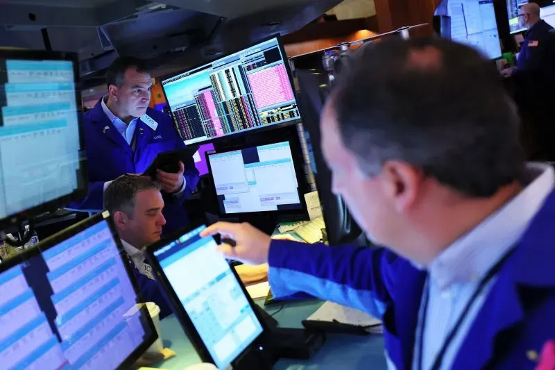 تجار في بورصة الأسهم يتابعون الشاشات المليئة بالبيانات المالية، وسط أجواء من التوتر الاقتصادي بسبب الحرب التجارية مع الصين.