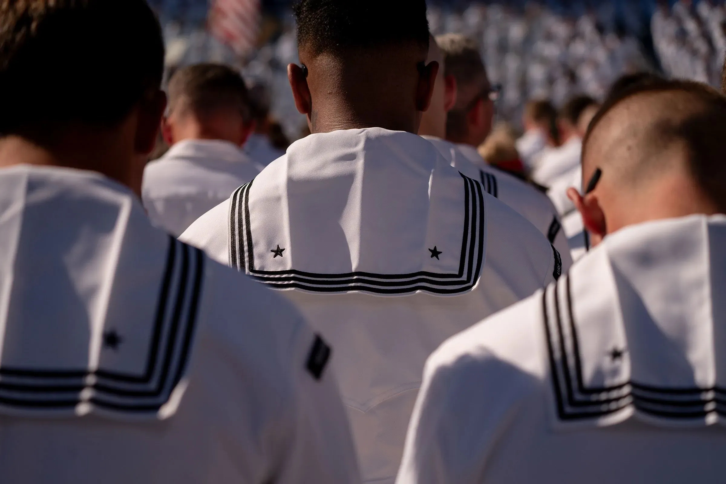 جنود بحريين يرتدون زيهم الرسمي، يظهرون من الخلف في تجمع رسمي، مما يعكس أهمية دعم القوات خلال الإغلاق الحكومي.