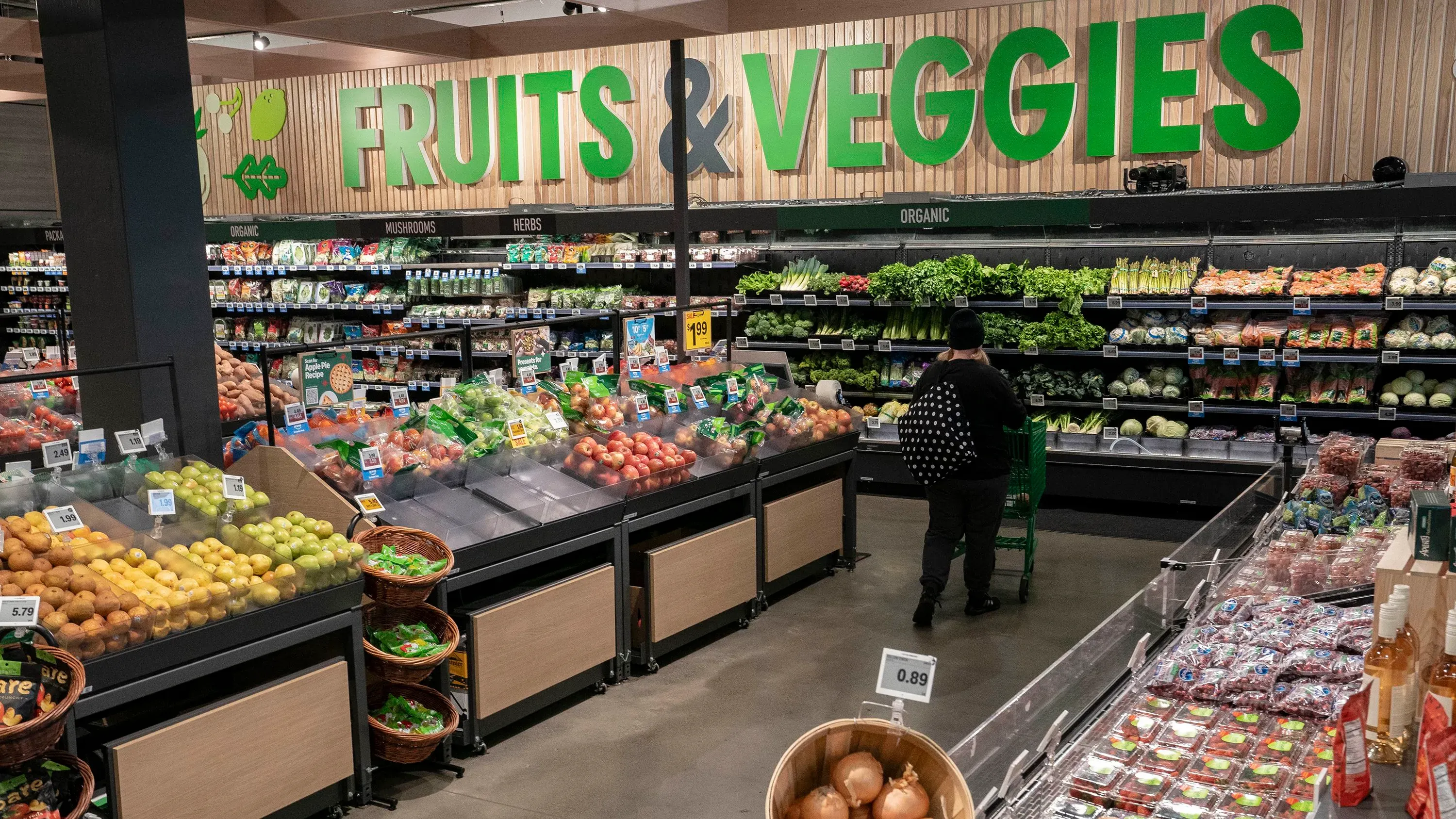 تظهر الصورة قسم الفواكه والخضروات في سوبرماركت، حيث يتم عرض مجموعة متنوعة من الفواكه والخضروات الطازجة.