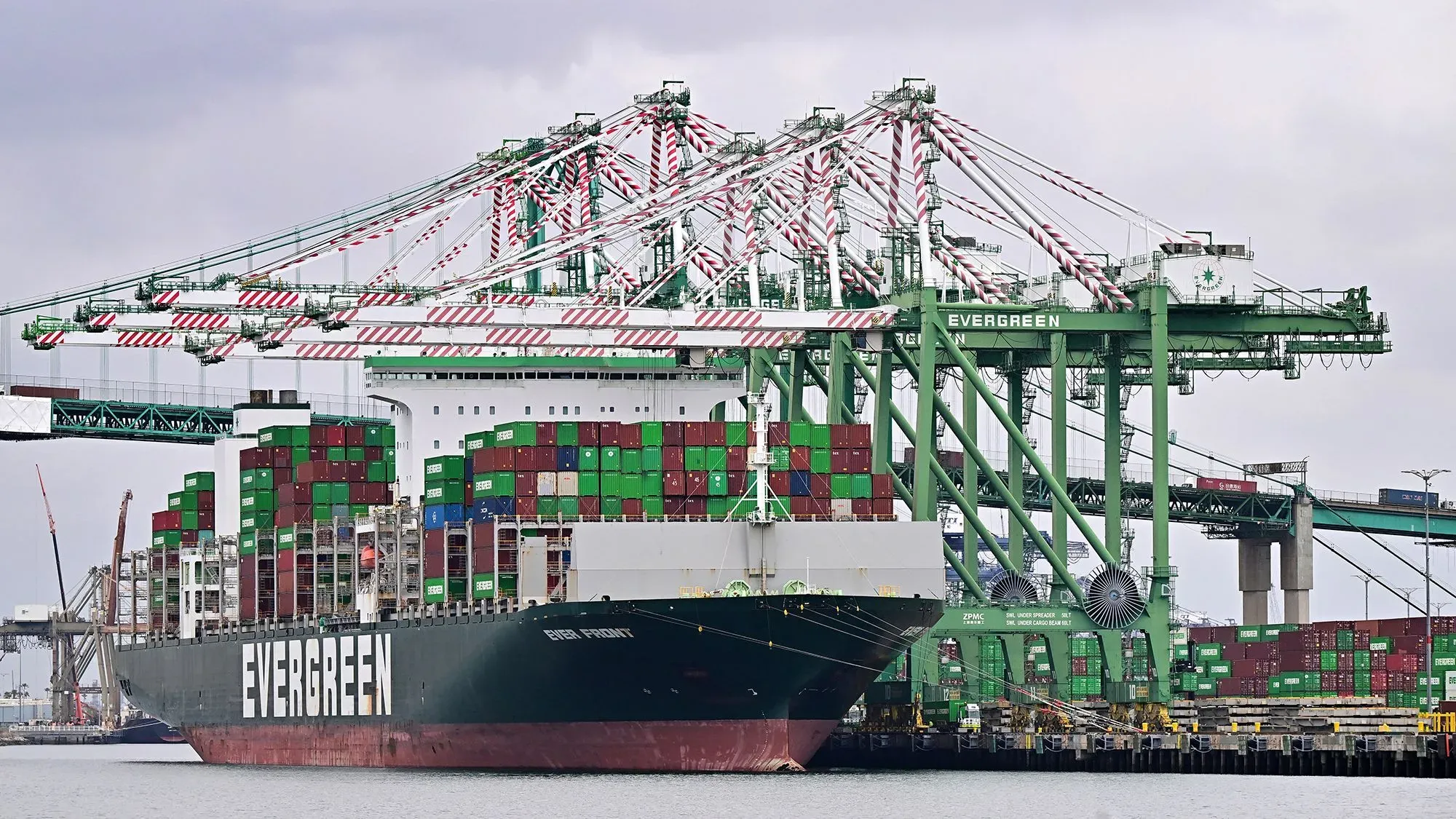 سفينة شحن تحمل حاويات ملونة في ميناء، تعكس تأثير الحرب التجارية على الاقتصاد العالمي والتجارة.