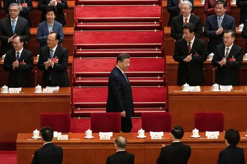 شي جين بينغ يسير أمام حشد من المسؤولين خلال اجتماع رسمي، وسط أجواء من التوترات التجارية بين الصين والولايات المتحدة.