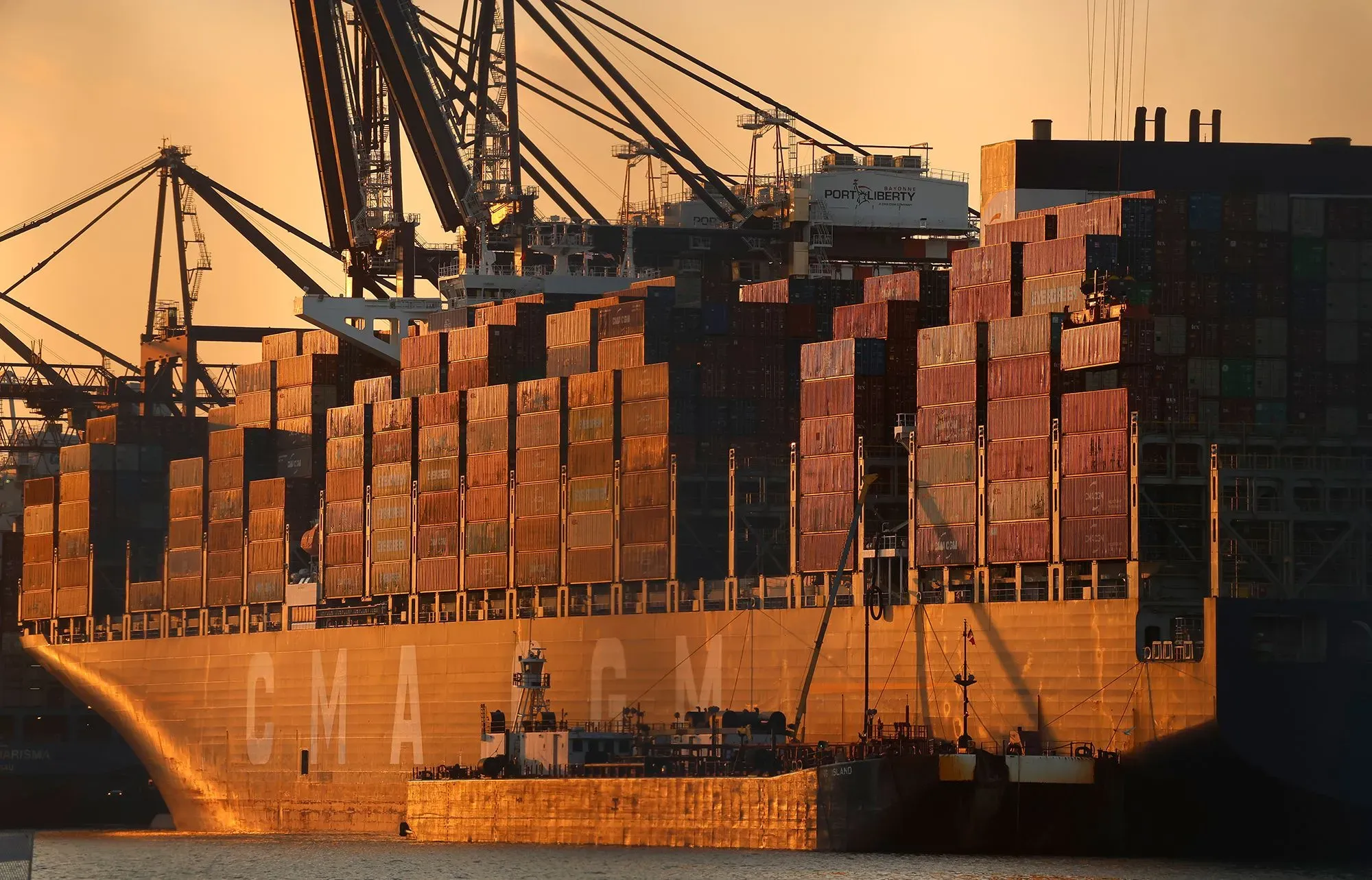 سفينة شحن كبيرة محملة بالحاويات في ميناء، تعكس إيرادات الرسوم الجمركية المرتفعة التي تجمعها الحكومة الأمريكية.
