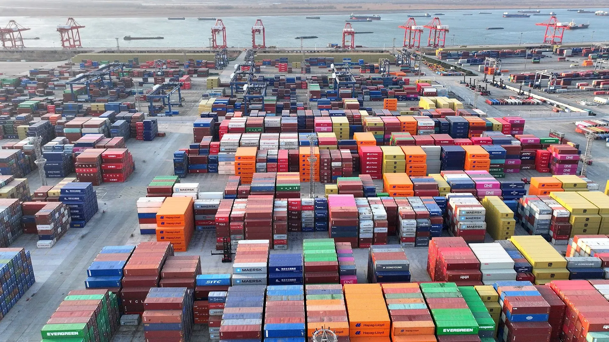 صورة لميناء يحتوي على حاويات شحن ملونة متراصة بشكل منظم، تعكس تأثير الرسوم الجمركية الجديدة على التجارة العالمية.