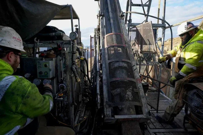 عمال في موقع تعدين في ألاسكا، يستخدمون معدات ثقيلة لاستخراج المعادن الحيوية مثل الكوبالت، وسط جدل بيئي حول المشروع.