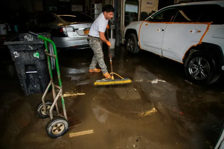 عامل ينظف المياه المتجمعة في ورشة سيارات بعد الفيضانات في نيوجيرسي، حيث تسببت العواصف في أضرار كبيرة وحالة طوارئ.
