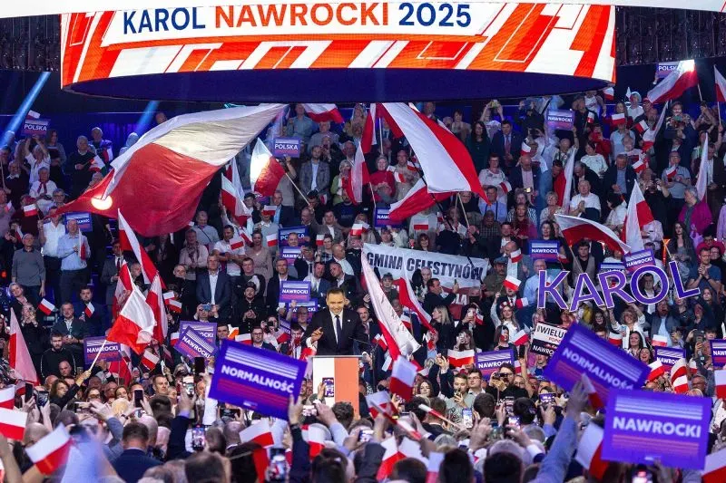 حشد كبير من مؤيدي كارول ناوروكي خلال تجمع انتخابي، يحملون لافتات وأعلام بولندية، بينما يتحدث ناوروكي على المنصة.