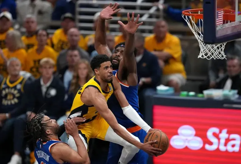 تايريس هاليبورتون يسجل سلة بينما يتصدى له لاعبان من فريق نيويورك نيكس، في مباراة حاسمة ضمن تصفيات الدوري الأمريكي للمحترفين.