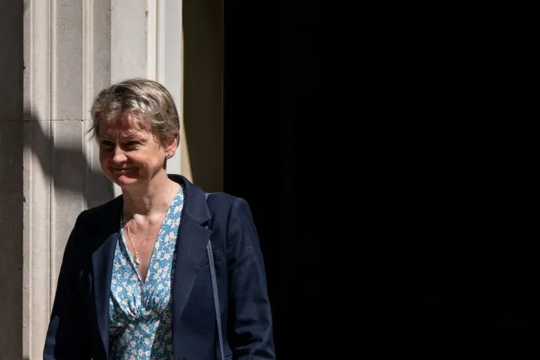 وزيرة الداخلية البريطانية إيفيت كوبر تخرج من مبنى حكومي، تعبيرها يدل على الجدية وسط تغييرات في سياسة اللجوء.