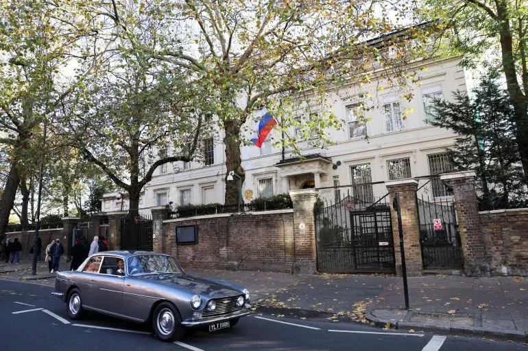 سفارة روسيا في لندن، تظهر العلم الروسي أمام المبنى، مع سيارة تمر بجوارها، تعكس التوترات الدبلوماسية الحالية بين المملكة المتحدة وروسيا.