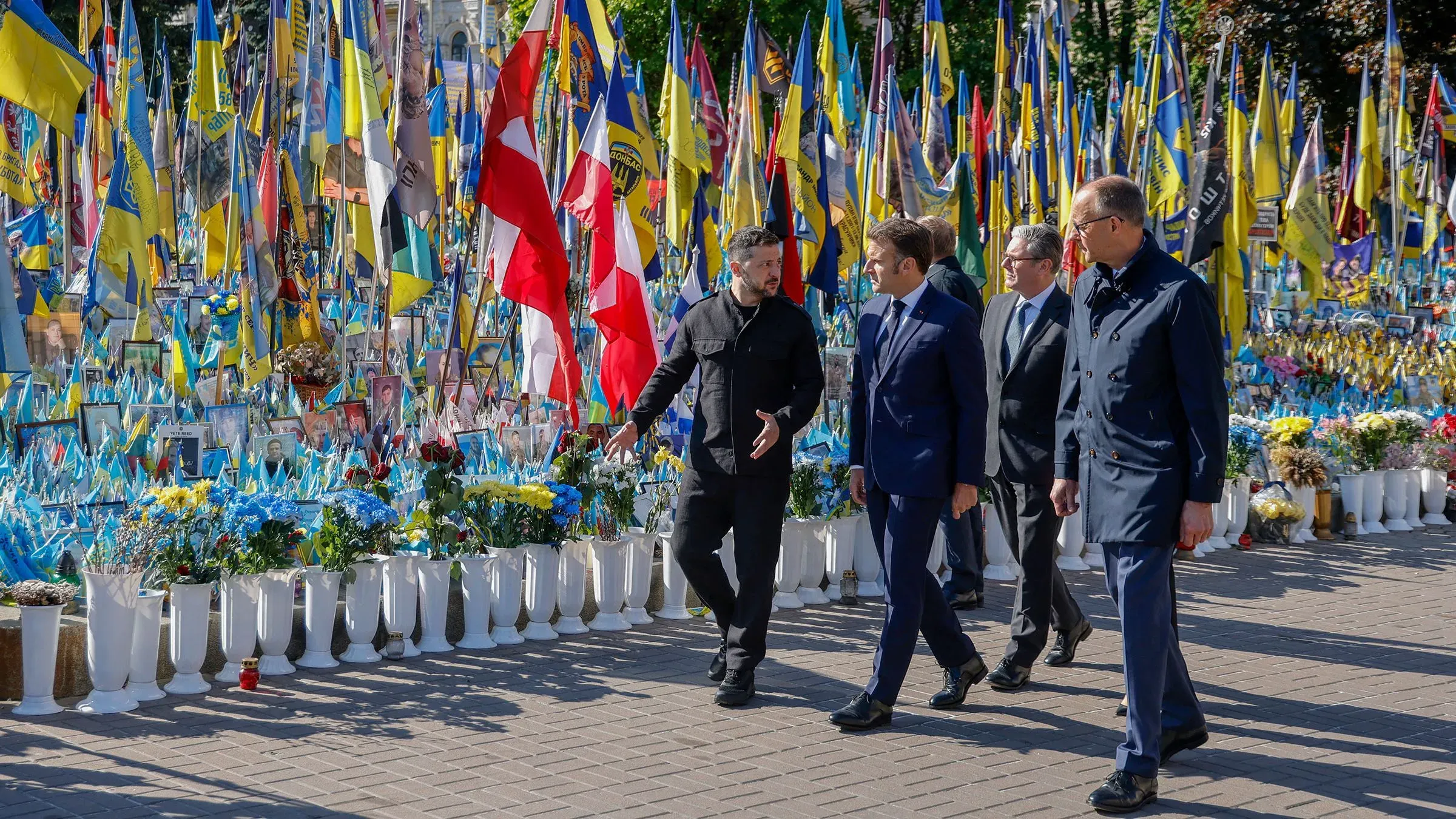 زيارة قادة أوروبيين لأوكرانيا، حيث يسيرون بين الأعلام والزهور، مما يعكس دعمهم في ظل التوترات الحالية.