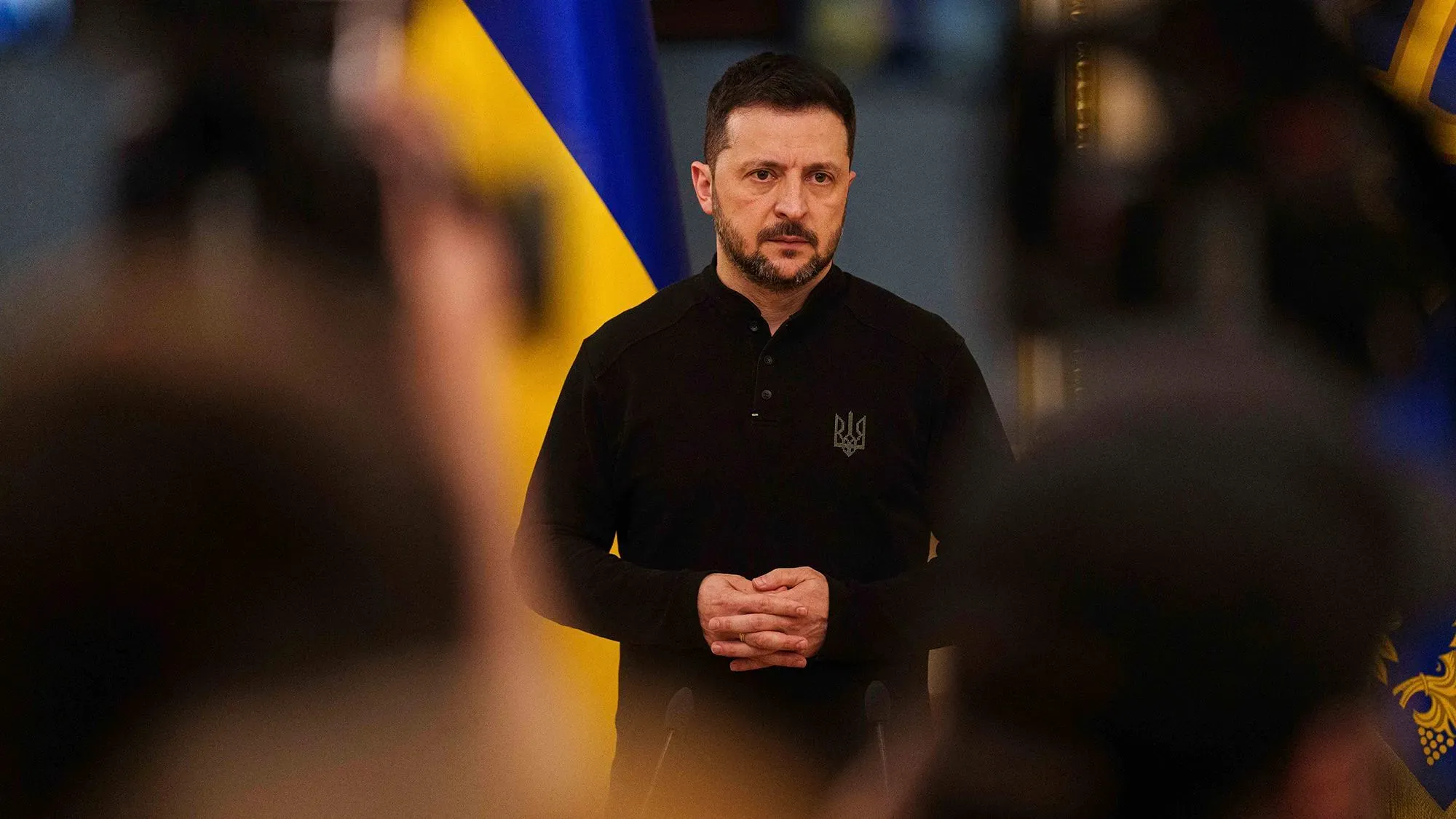 الرئيس الأوكراني فولوديمير زيلينسكي يتحدث خلال مؤتمر صحفي، مع العلم الأوكراني خلفه، مع التركيز على الوضع الأمني في أوكرانيا.