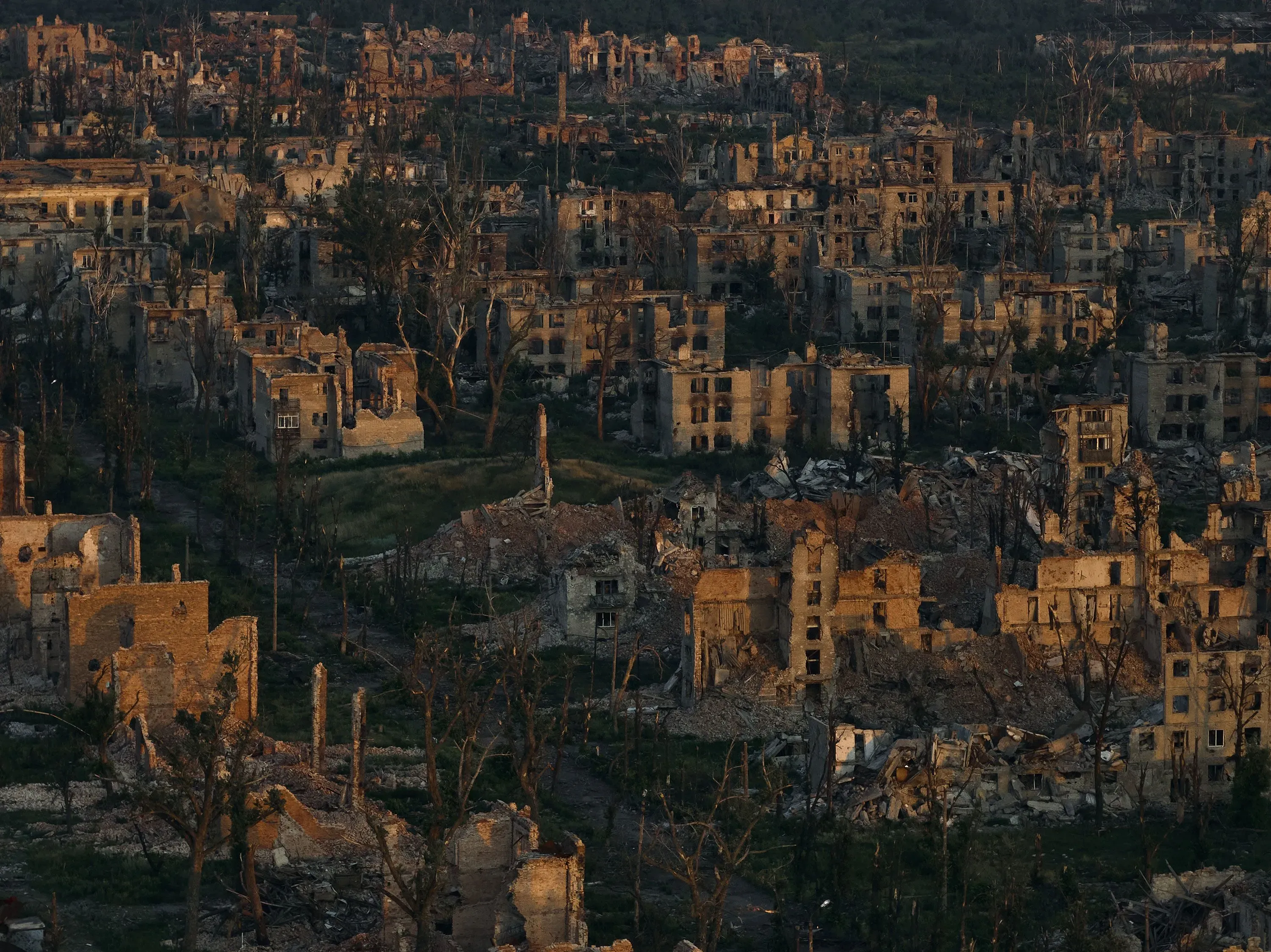 منظر لمدينة مدمرة تظهر مباني مهدمة وأشجار جرداء، تعكس آثار الحرب في أوكرانيا وتأثيرها المدمر على البنية التحتية.