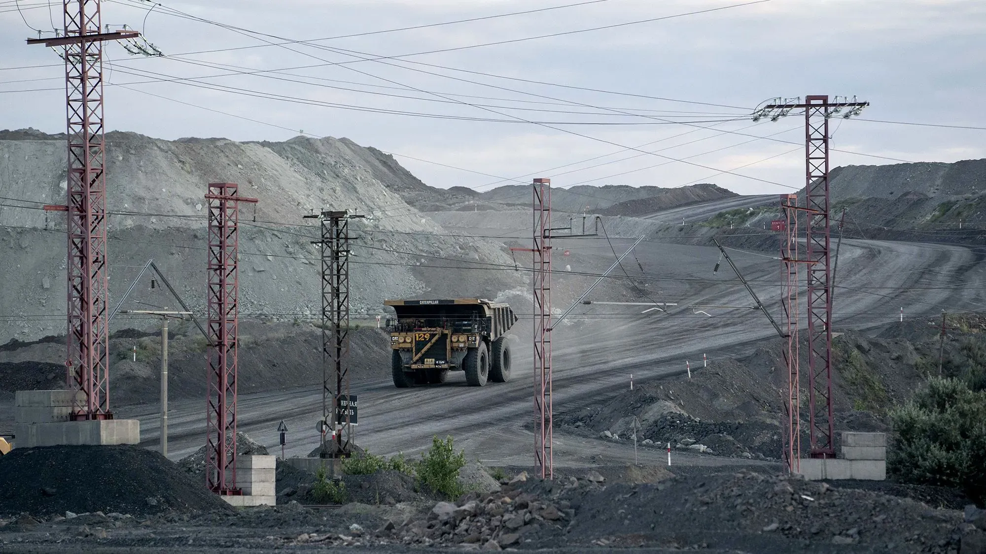 مشهد لموقع تعدين في أوكرانيا، حيث تسير شاحنة كبيرة على طريق محاط بتضاريس جبلية، مما يبرز أهمية الموارد المعدنية في سياق الدعم العسكري الأمريكي.