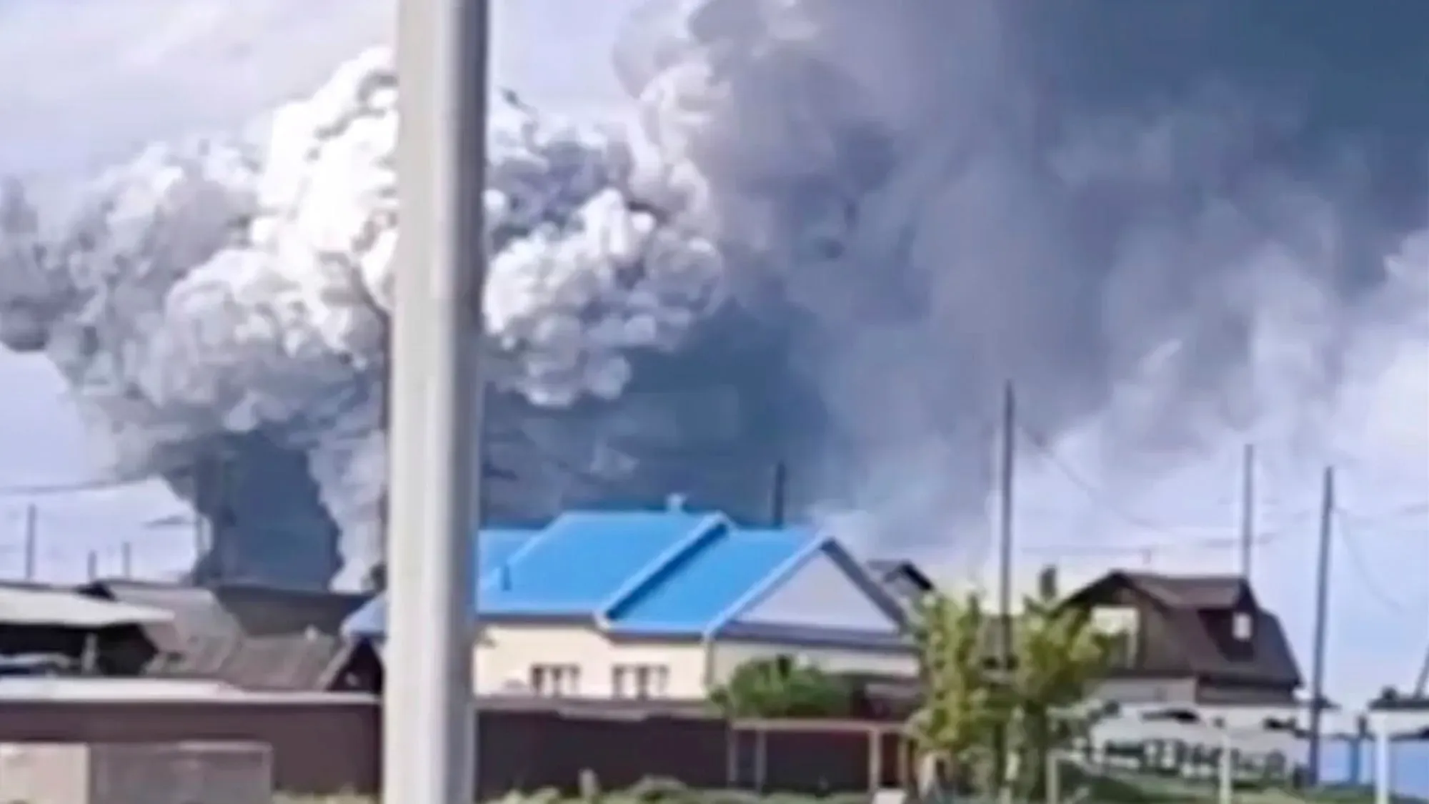 دخان كثيف يتصاعد من موقع انفجار في منطقة روسية، مع منازل قريبة تُظهر آثار الهجوم الأوكراني بالطائرات بدون طيار.