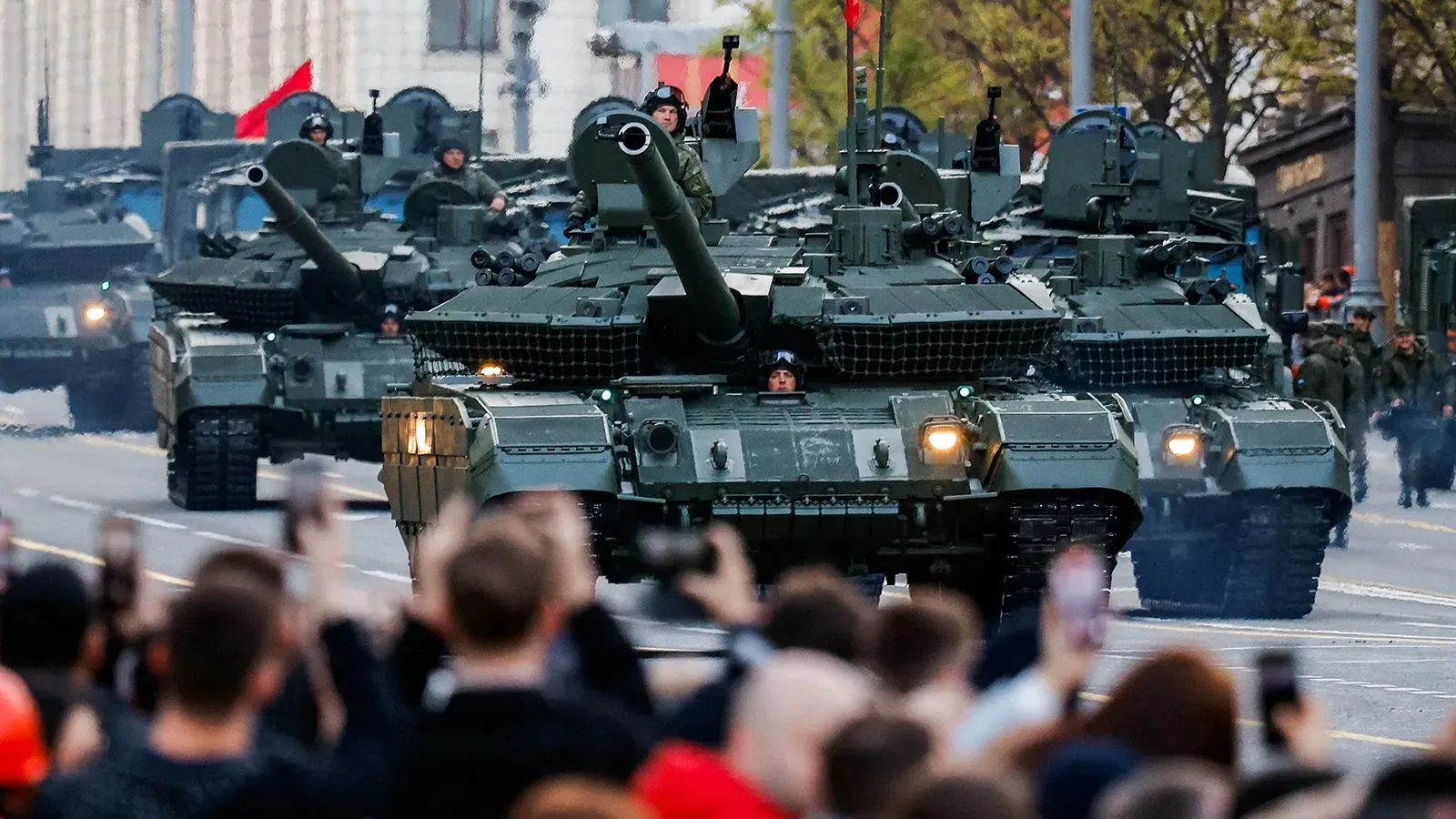 دبابات عسكرية تسير في عرض بموسكو، بينما يتجمع حشد من الناس لتوثيق الحدث. العرض يأتي قبل احتفالات عيد النصر.