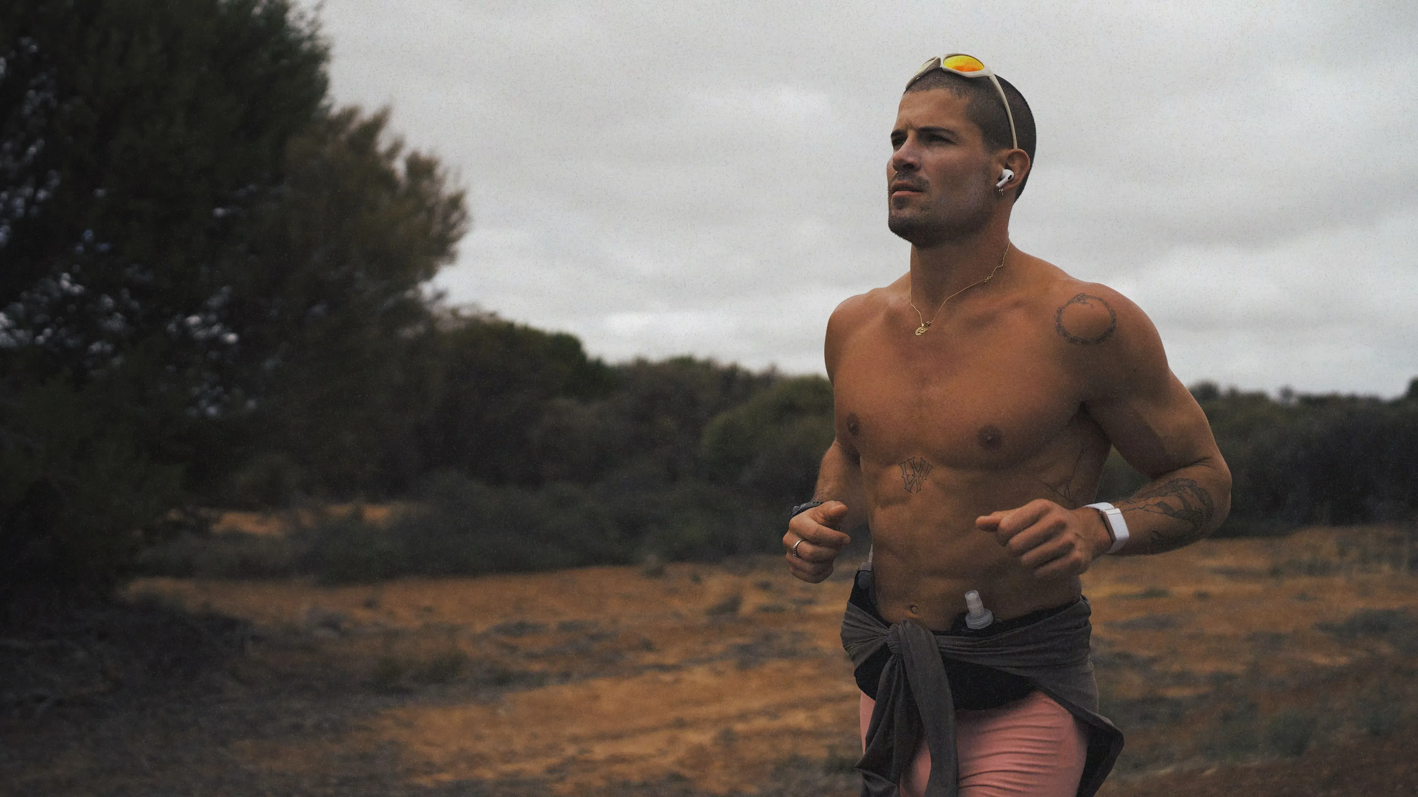 عداء يتدرب في منطقة طبيعية، يرتدي سماعات أذن، ويظهر التركيز والعزيمة خلال مسيرته الطويلة لاجتياز أستراليا.