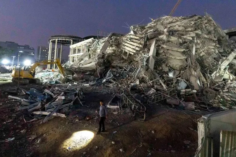 موقع انهيار ناطحة سحاب قيد الإنشاء في بانكوك، مع رجال إنقاذ يبحثون عن المفقودين وسط الأنقاض بعد زلزال قوي.