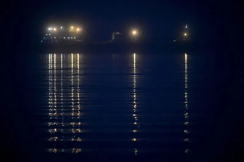 عوامات مضيئة على سطح الماء تعكس أضواء سفينة في ظلام الليل، تشير إلى نشاط في مياه بحر البلطيق وسط مخاوف من أضرار البنية التحتية.