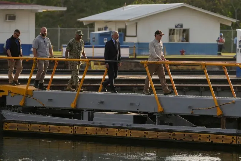 زيارة وزير الدفاع الأمريكي إلى قناة بنما، حيث يسير مع وفد رسمي على جسر مطل على القناة، مع وجود مباني خلفية.