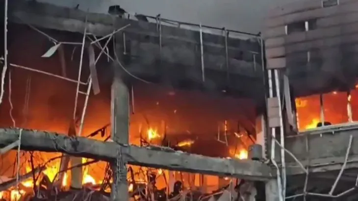 مبنى محترق في إيران نتيجة الحرب، مع تصاعد الدخان والنيران، مما يعكس تأثير النزاع على المدنيين والبنية التحتية.