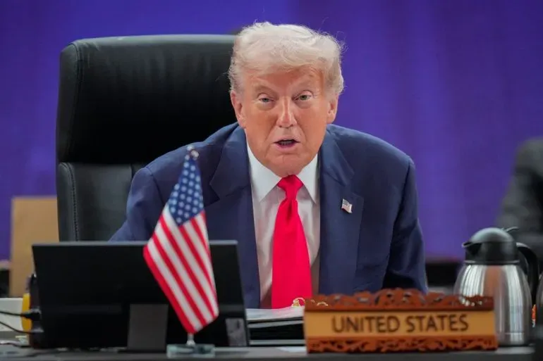 ترامب يتحدث خلال قمة آسيان في كوالالمبور، مع العلم الأمريكي أمامه، في سياق مفاوضات التجارة مع الصين.