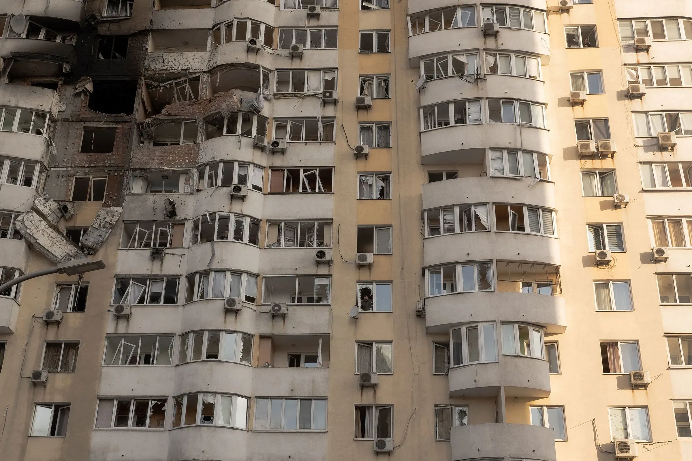 واجهة مبنى سكني متضرر في أوكرانيا، تظهر نوافذ محطمة وأضرار واضحة، تعكس آثار النزاع المسلح وتأثيره على المدنيين.