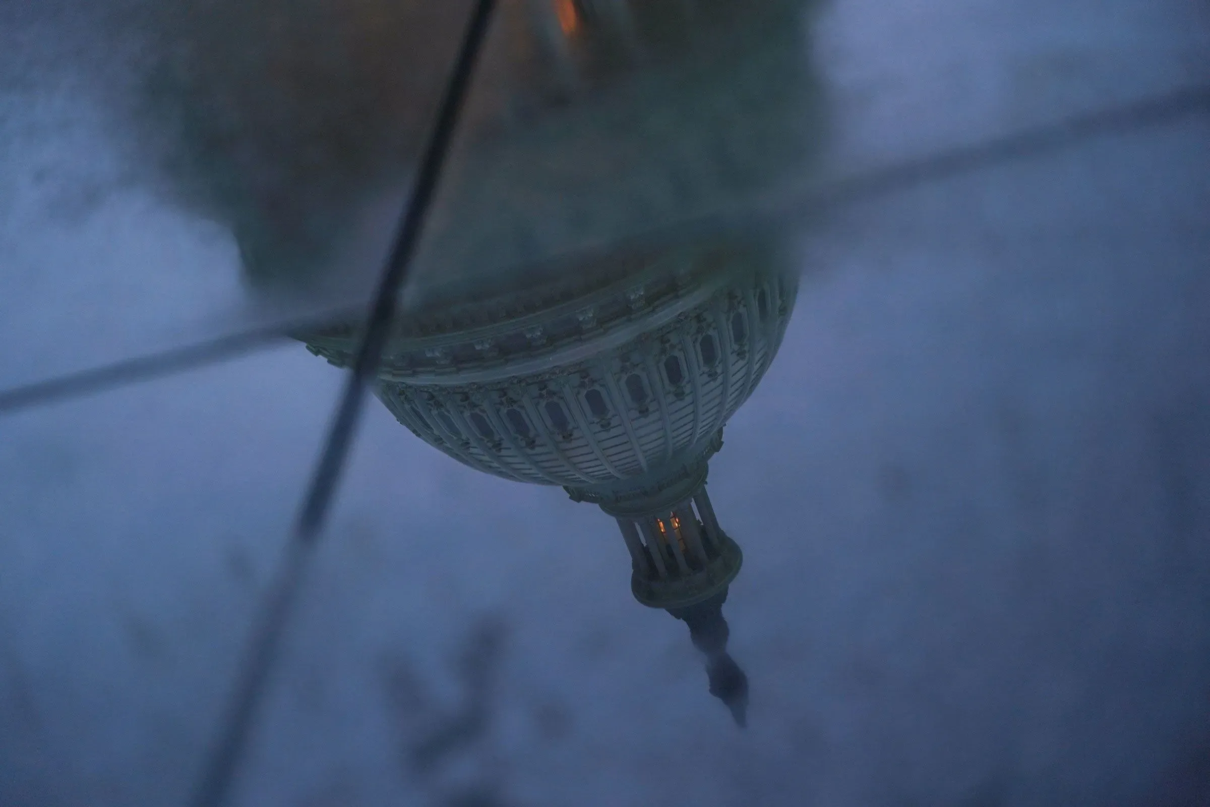 انعكاس لمبنى الكابيتول الأمريكي في بركة ماء، يعكس حالة عدم اليقين السياسي بعد الإغلاق الحكومي.