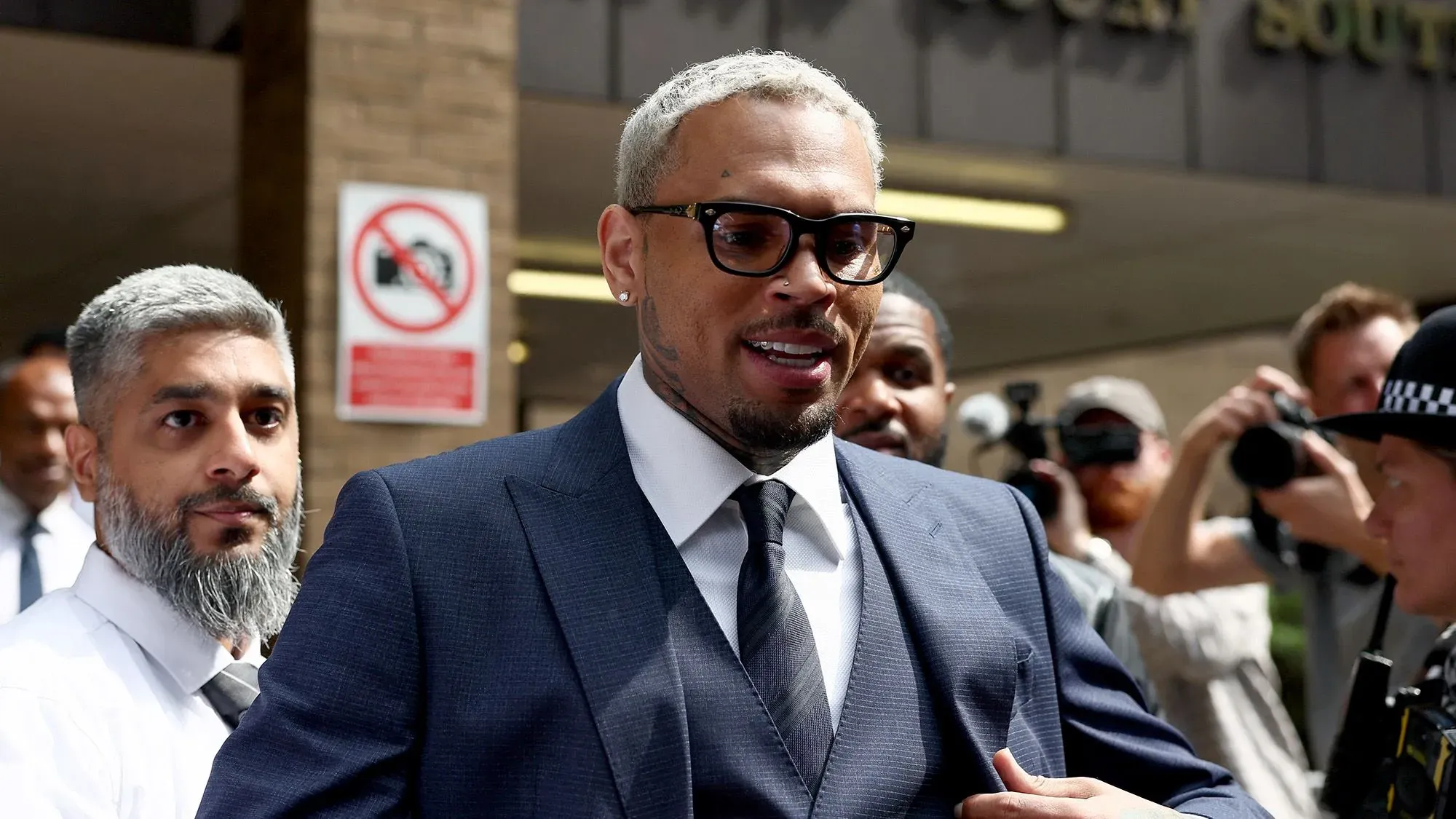 المغني كريس براون يغادر المحكمة مرتديًا بدلة رسمية، وسط حشد من المعجبين والصحفيين بعد جلسة استماع تتعلق بتهم الاعتداء.