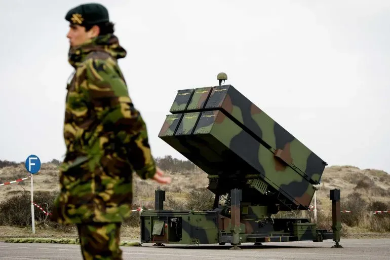 جندي يرتدي زيًا عسكريًا يقف بجوار نظام صواريخ أرض-جو متقدم (NASAMS)، وذلك في إطار صفقة تسليح محتملة لمصر.
