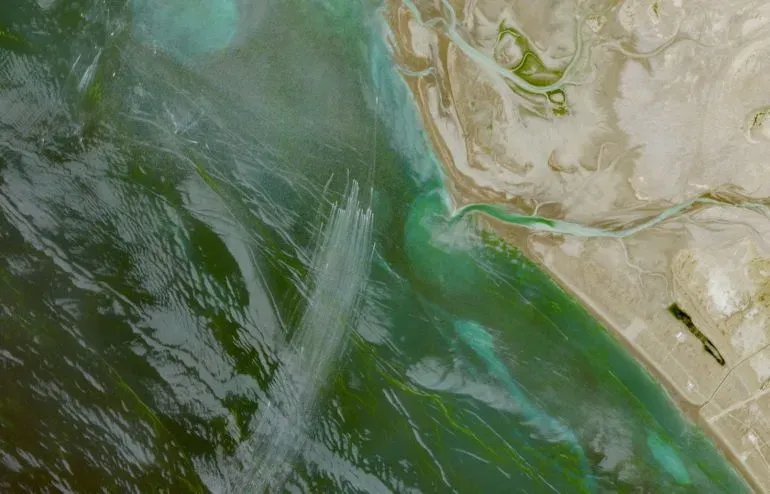 صورة جوية لمضيق هرمز تُظهر المياه المتقلبة واليابسة المحيطة، تعكس التوترات الجيوسياسية وتأثيرها على حركة الملاحة البحرية.