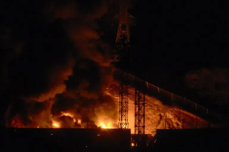 دخان ونيران تتصاعد من موقع غارة جوية أمريكية على فنزويلا، مشيرة إلى تصاعد التوترات العسكرية والاعتقالات.