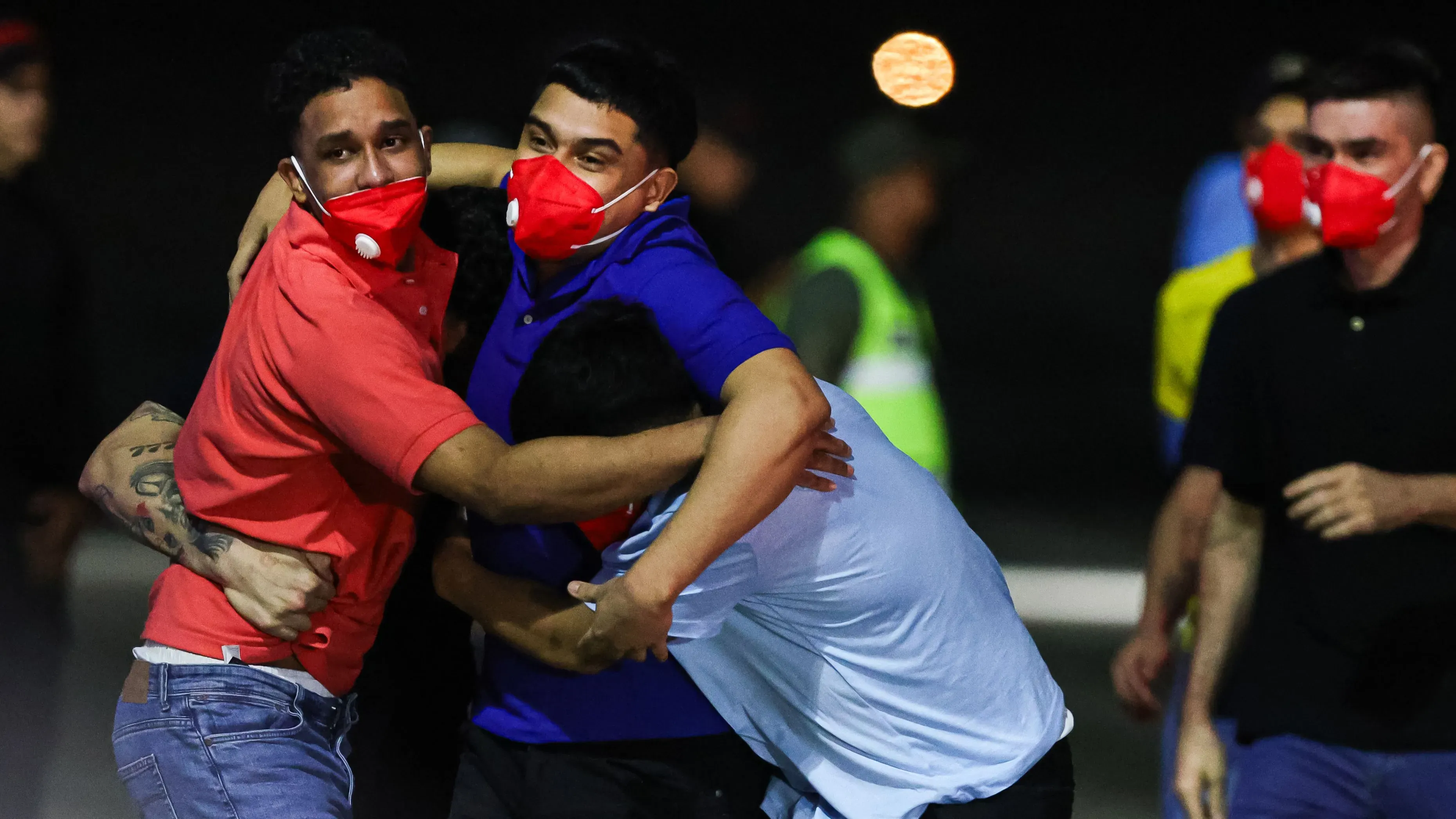 أشخاص يحتضنون بعضهم في مطار سيمون بوليفار الدولي بعد عودة المهاجرين الفنزويليين المفرج عنهم من السلفادور، مع مشاعر الفرح والتوتر.