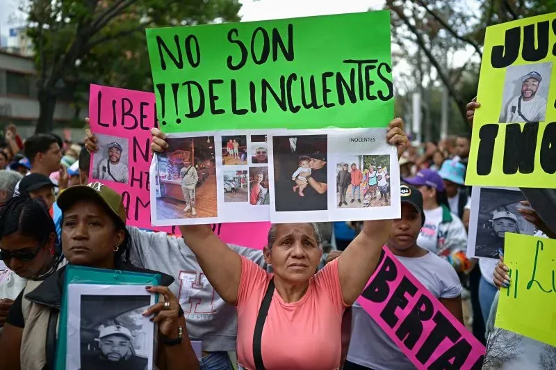 تظهر امرأة تحتج في شوارع كاراكاس حاملة لافتة مكتوب عليها "ليسوا مجرمين" وصور لأحبائها المرحلين إلى السلفادور.