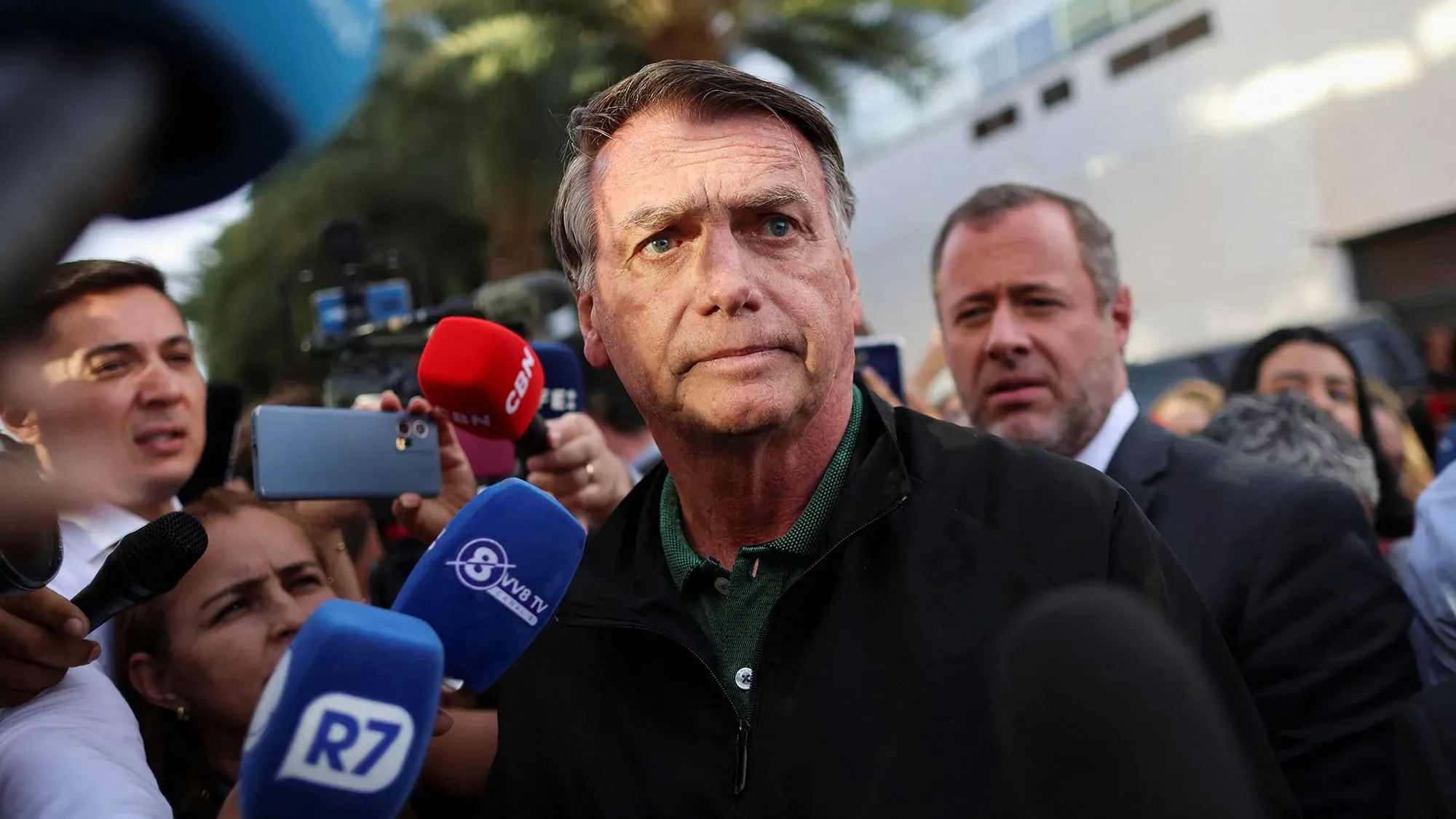 الرئيس البرازيلي السابق جايير بولسونارو محاط بالصحفيين أثناء محاكمته بتهمة محاولة الانقلاب، مع توتر واضح على وجهه.