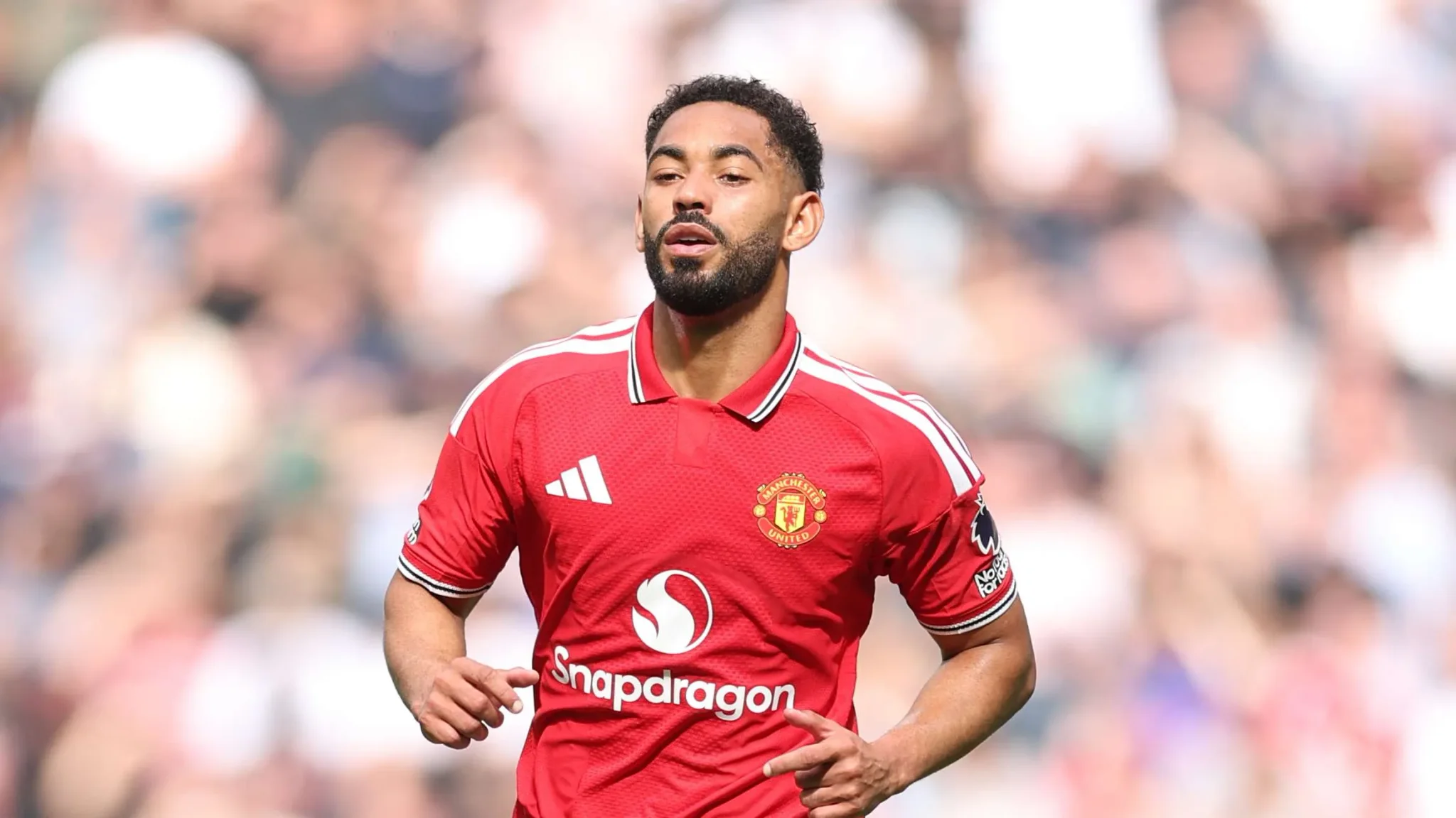 لاعب مانشستر يونايتد يرتدي القميص الأحمر خلال مباراة الدوري الإنجليزي، مع تركيز على أداء الفريق في غياب المهاجم الأساسي بنجامين سيسكو.