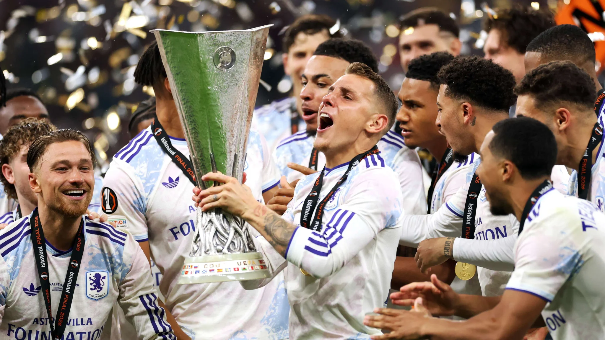 لاعبو أستون فيلا يحتفلون بفوزهم بلقب الدوري الأوروبي 2023، مع لوكاس ديغني حاملًا الكأس وسط فرحة الفريق.