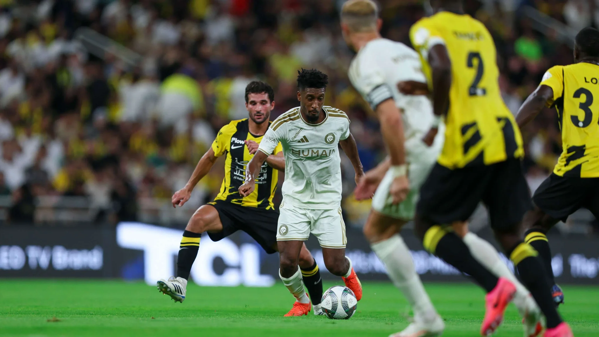 لاعب من فريق النصر يسيطر على الكرة وسط لاعبي الاتحاد خلال مباراة في دوري Roshn السعودي للمحترفين.