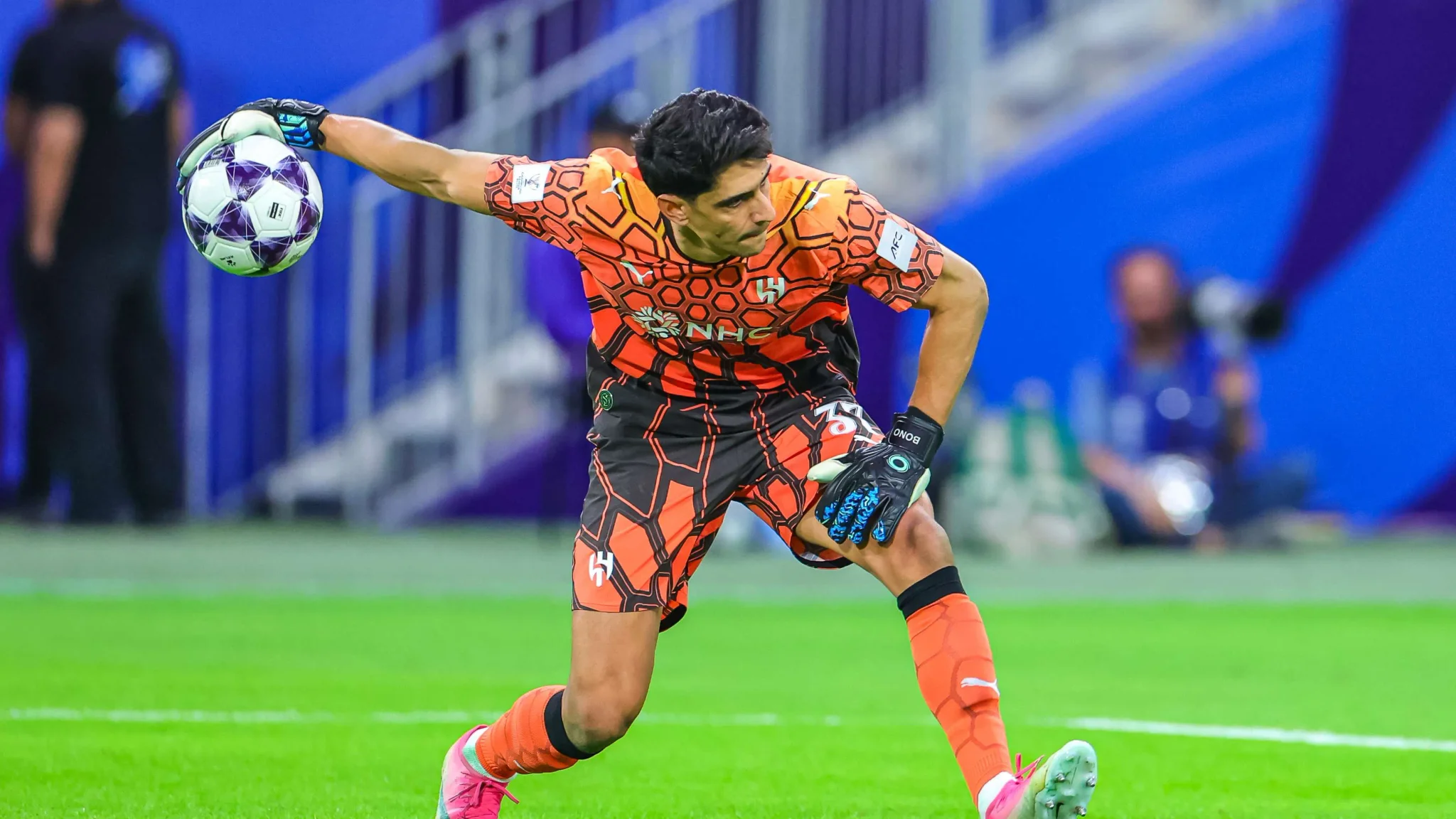 حارس الهلال المغربي ياسين بونو يلتقط الكرة أثناء مباراة دوري أبطال آسيا، معبرًا عن تواضع القيادة وروح الفريق.