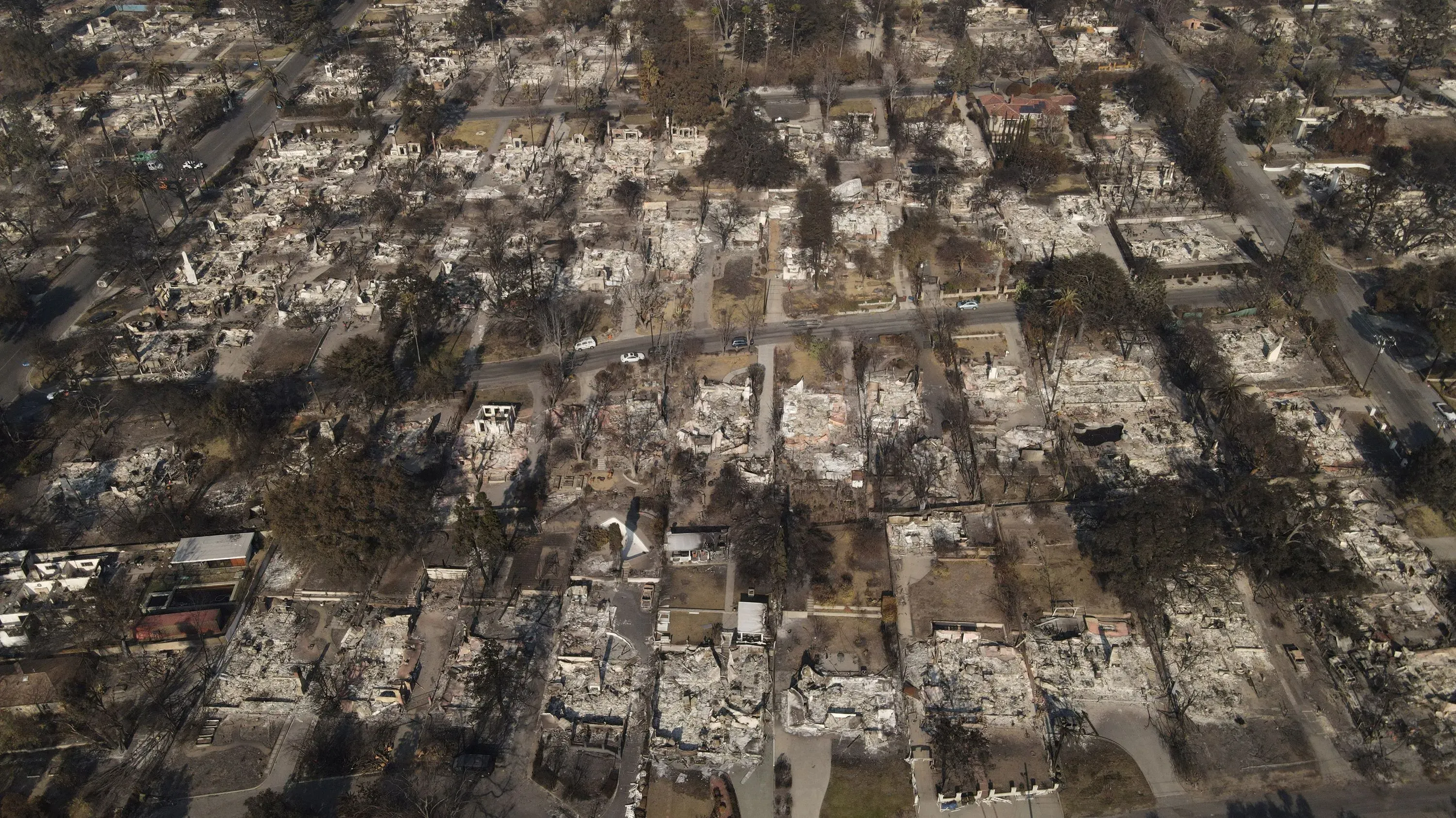 مشهد جوي لمنطقة دمرها حريق إيتون، يُظهر منازل مدمرة بالكامل وأشجاراً محترقة، مما يبرز آثار الكارثة المأساوية.