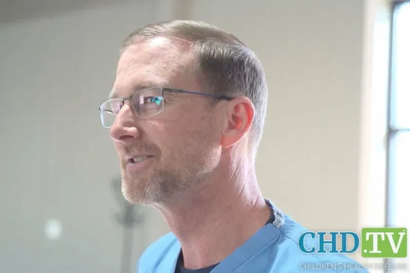 طبيب يرتدي زيًا طبيًا يتحدث مع الآباء والأطفال في عيادة مؤقتة، مصاب بطفح الحصبة، في تكساس وسط تفشي المرض.