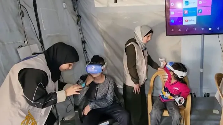 أطفال فلسطينيون يرتدون سماعات الواقع الافتراضي في خيمة مؤقتة بغزة، يتلقون الدعم النفسي للتعافي من آثار الحرب.